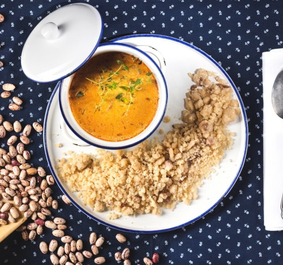 Millet with bean soup in white dish on blue cloth with spoon