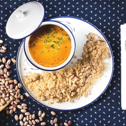 Millet with bean soup in white dish on blue cloth with spoon
