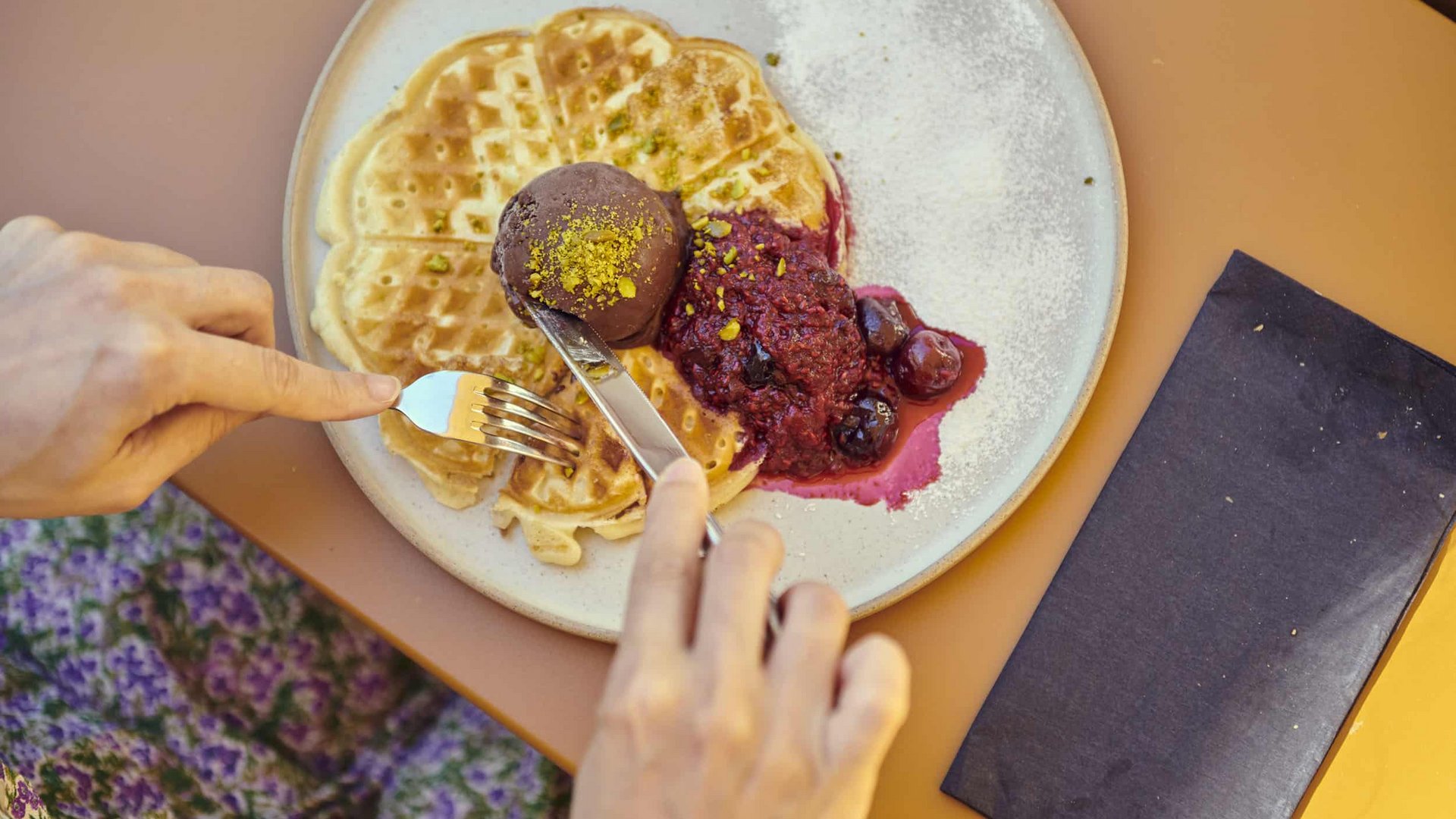 Waffle with dark ice cream and berry compote on a white plate