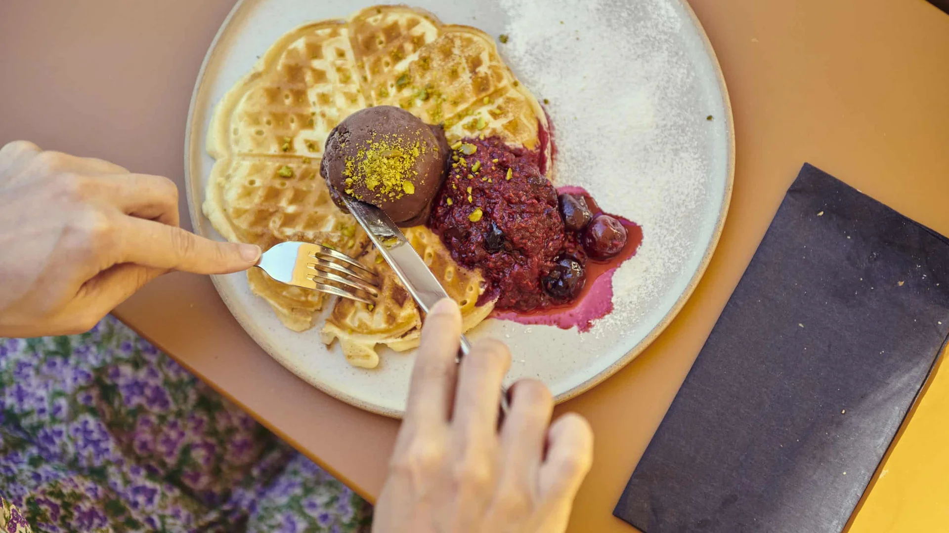 Waffle with dark ice cream and berry compote on a white plate