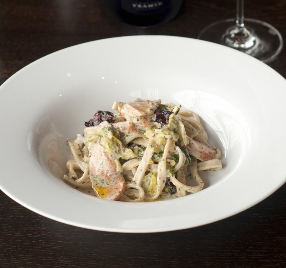 Pasta with creamy sauce served with a glass of white wine and a wine bottle
