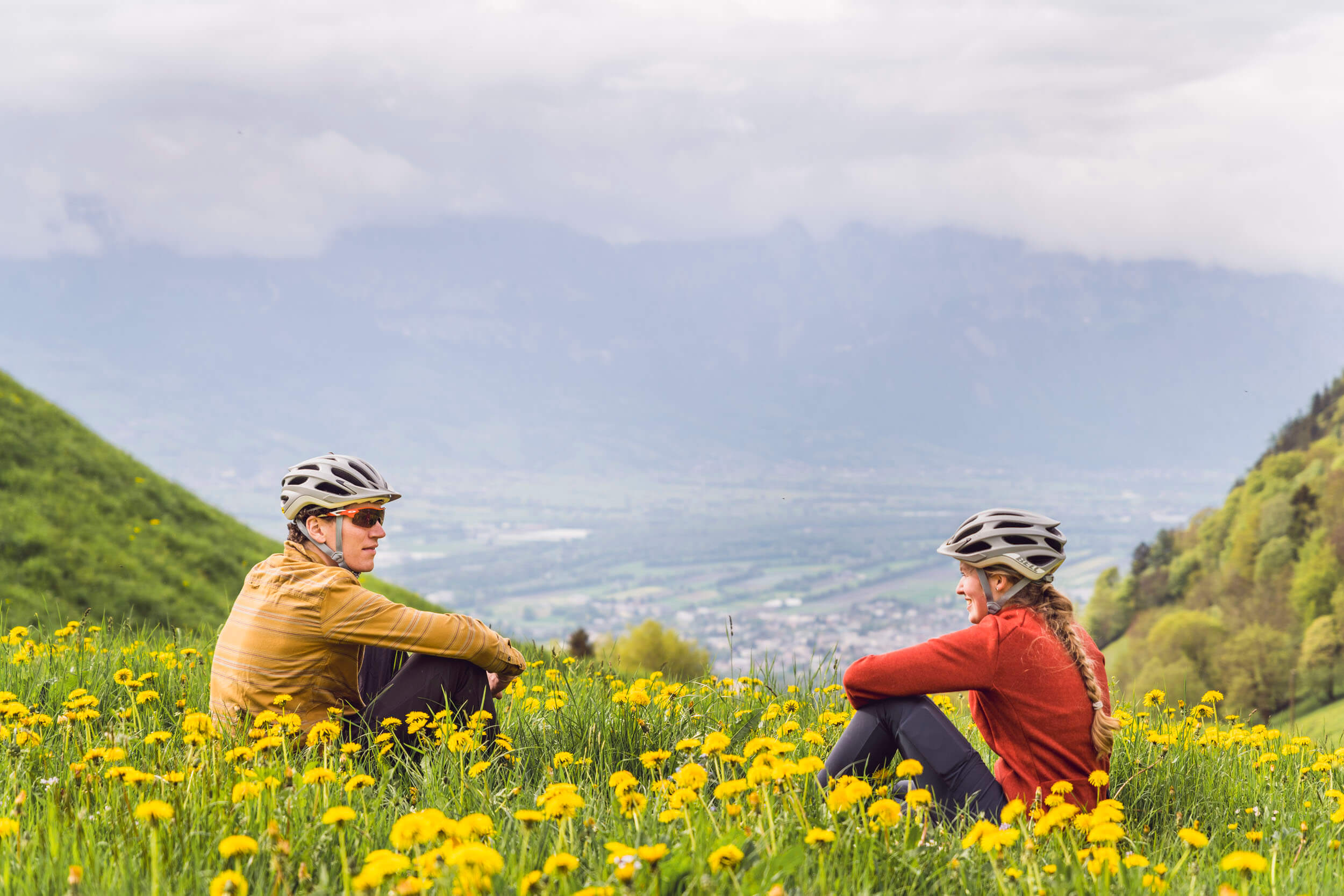 Zwei Radfahrer sitzen im Blumengarten in den Bergen und genießen die Aussicht