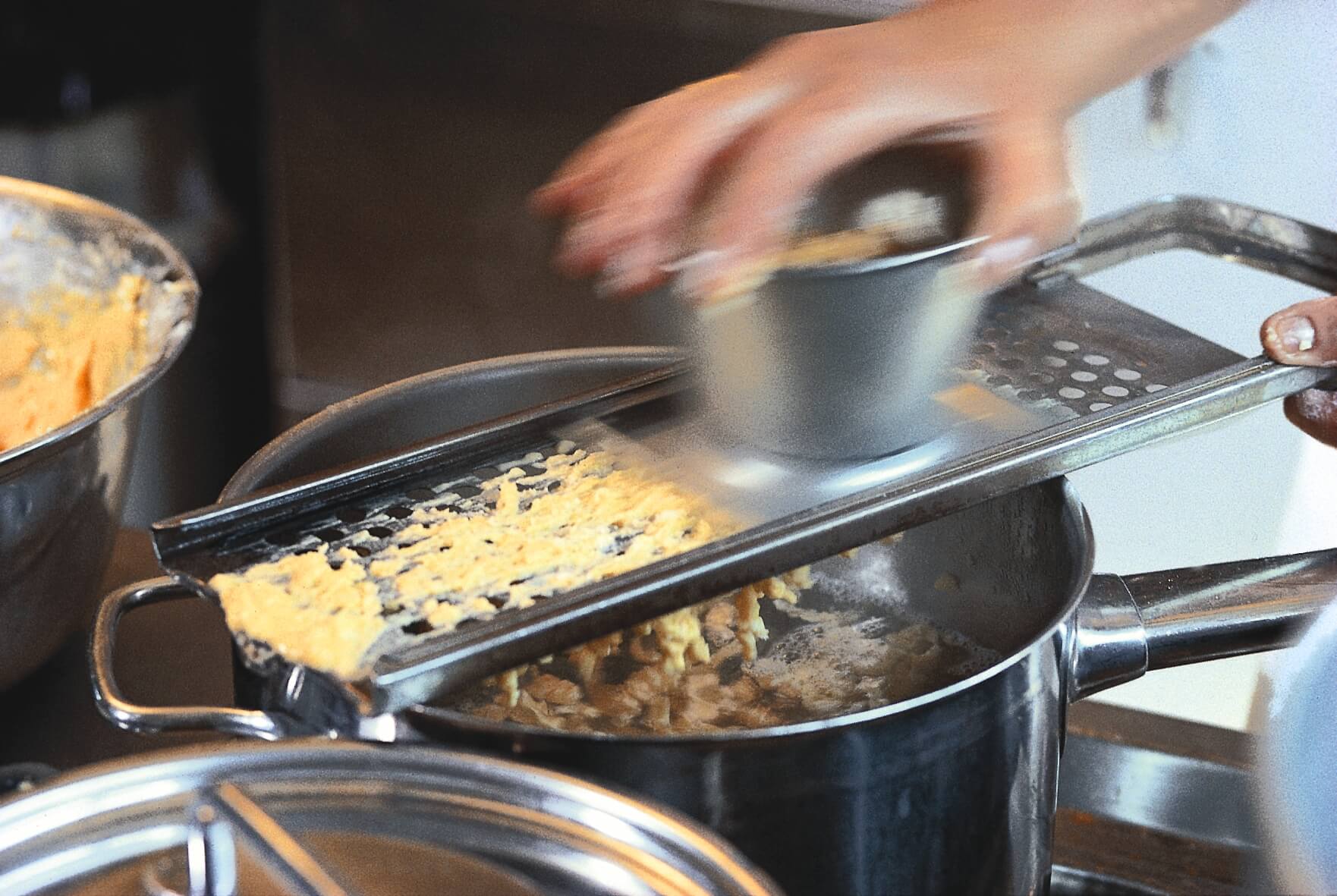 Person grating food into a cooking pot
