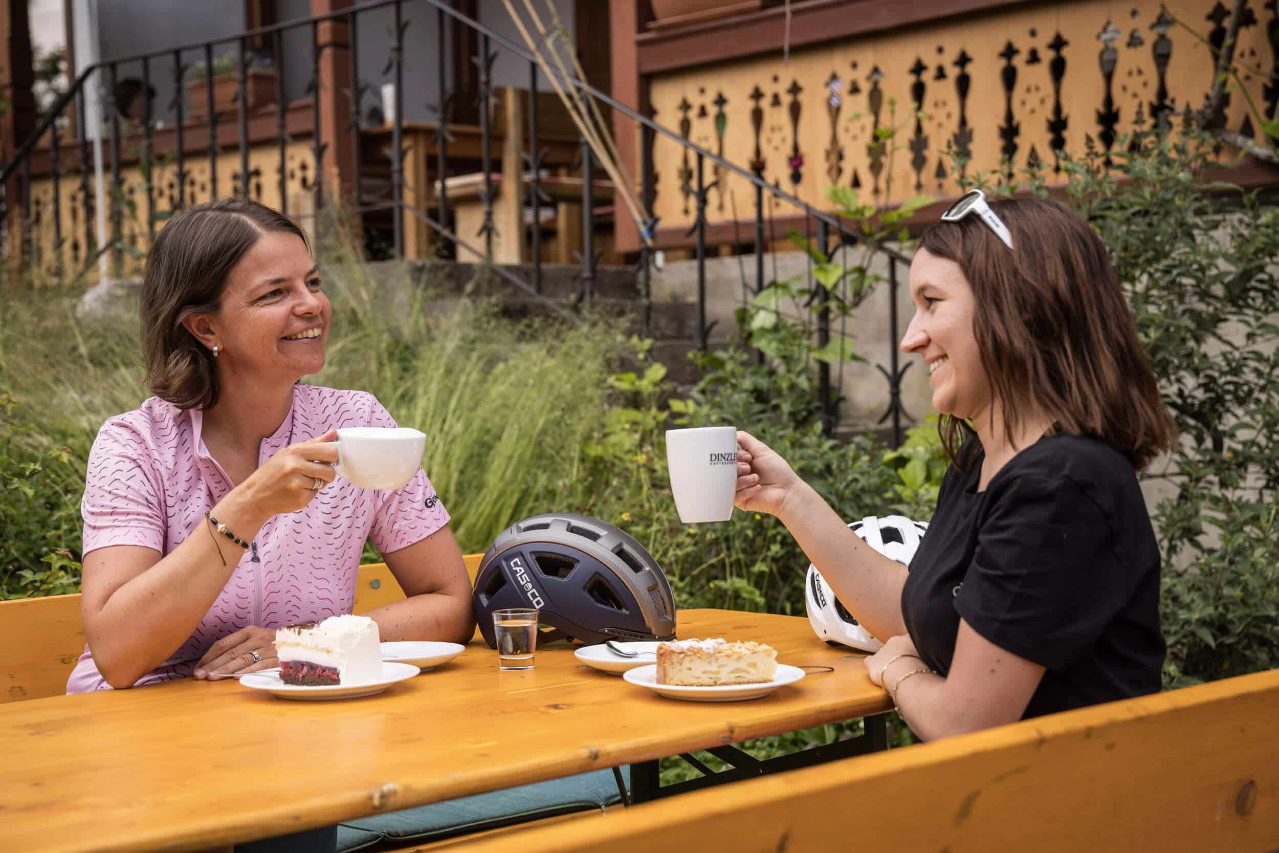 Zwei Frauen trinken Kaffee und essen Kuchen im Freien an einem Holztisch