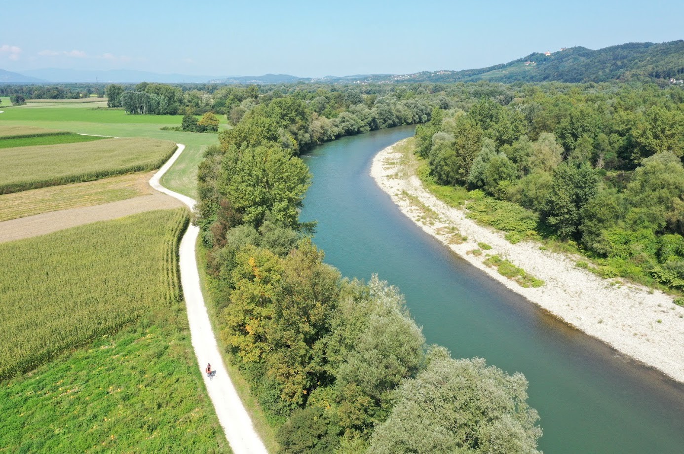 Fluss mit Wanderweg und grünen Feldern an einem sonnigen Tag