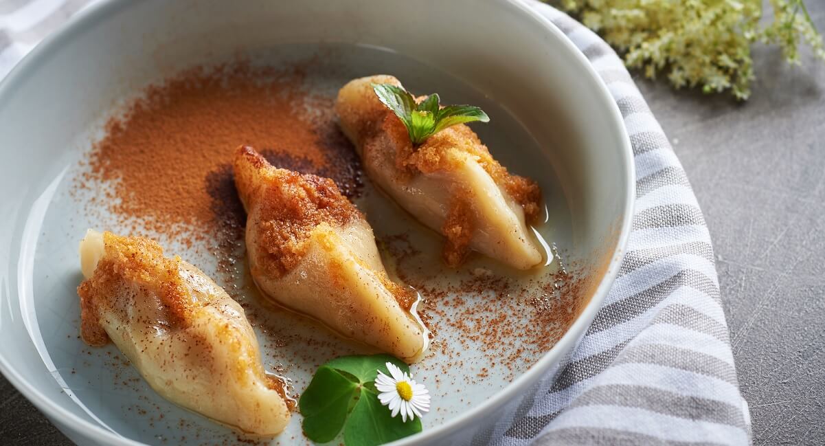 Three filled dumplings topped with cinnamon and butter on a plate