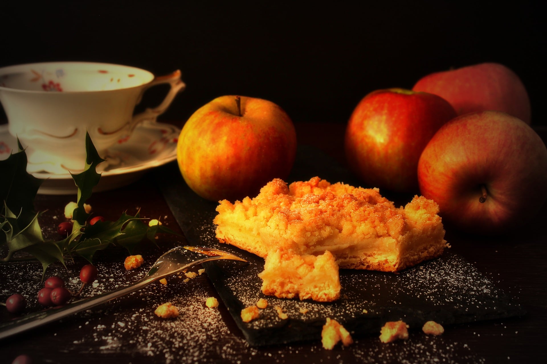 Apple cake with apples, coffee cup and decoration on dark surface