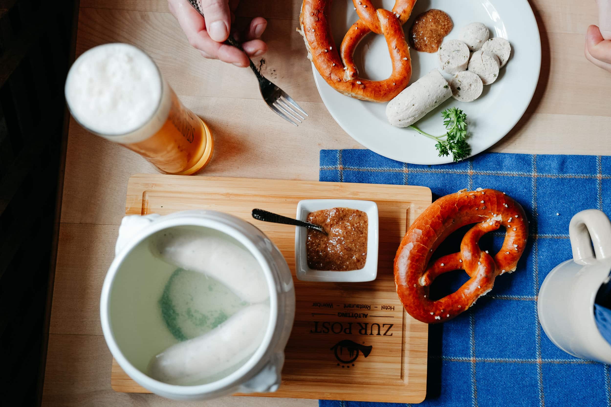 Bayerische Weißwurst mit Brezen, süßem Senf und Bier auf einem Holztisch