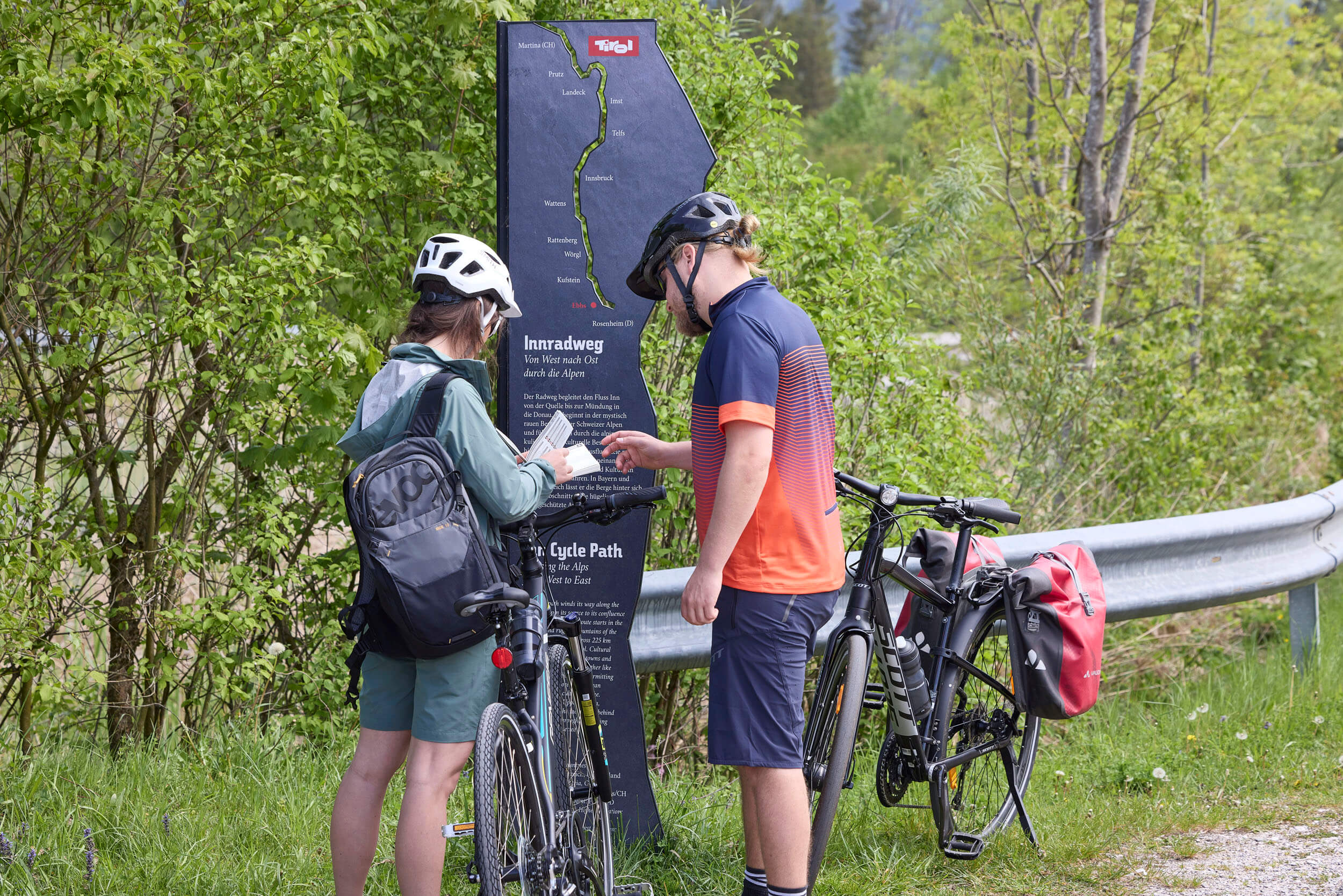 Packliste für einen perfekten Radurlaub © TVB Kufsteinerland - Simon Hausberger Zwei Radfahrer lesen eine Infotafel am Innradweg in Tirol