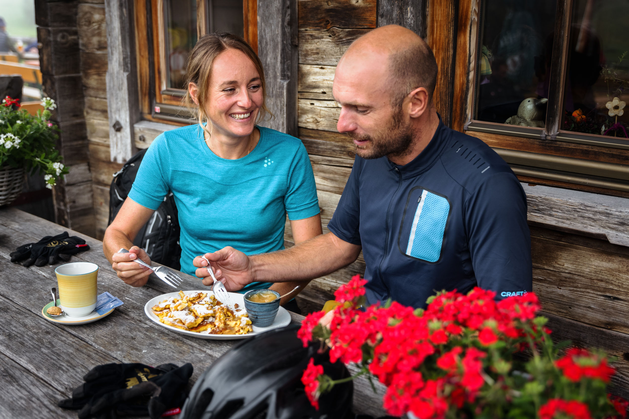 Couple eating cake and drinking coffee at wooden table outside cabin