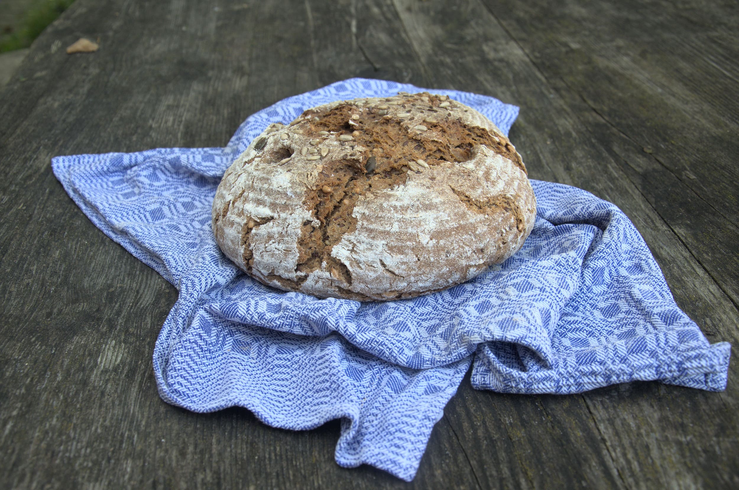 Round rustic bread on blue cloth on wooden table