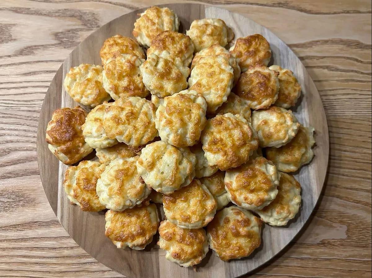 Plate of small baked cheese pastries on wooden surface