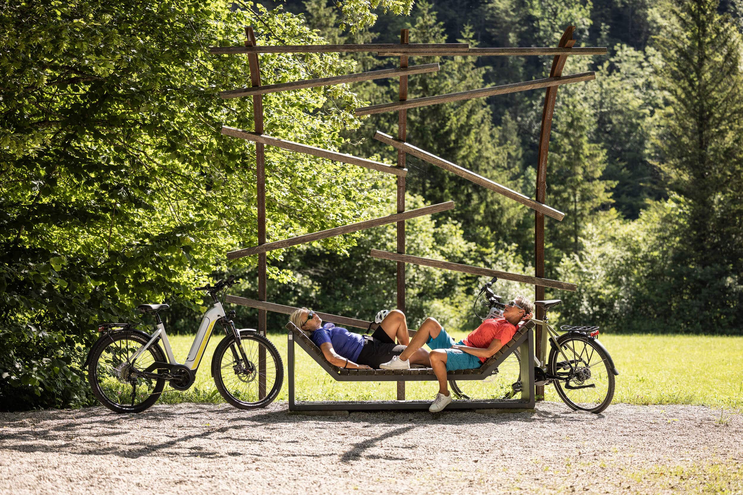 Zwei Personen ruhen sich auf einer modernen Bank im Park neben Fahrrädern aus
