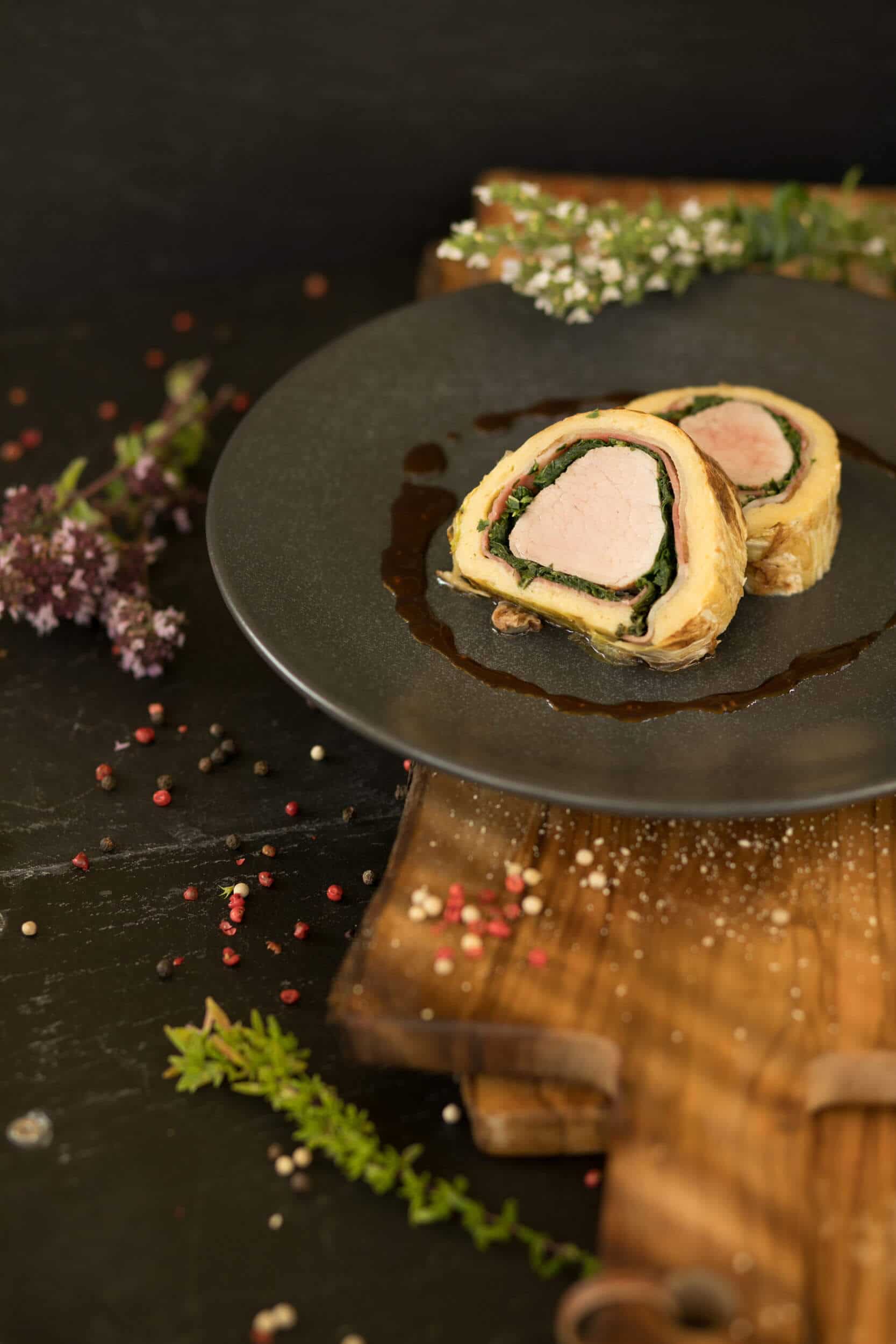 Plated stuffed meat dish on a black plate with sauce