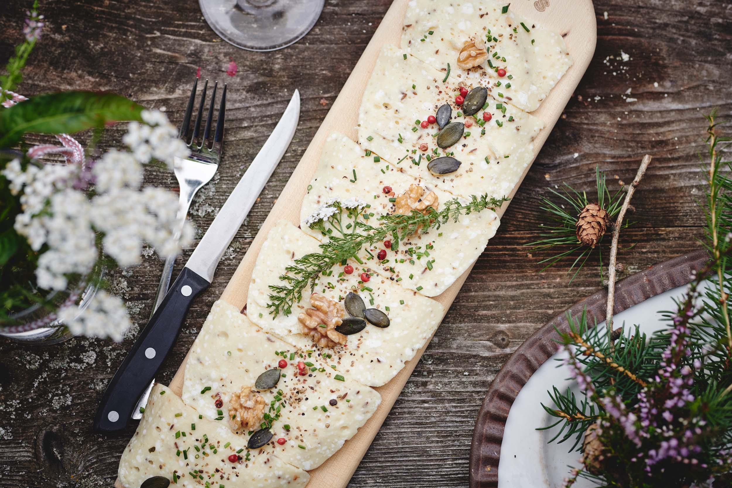 Cheese with herbs, nuts, and seeds served on a wooden board