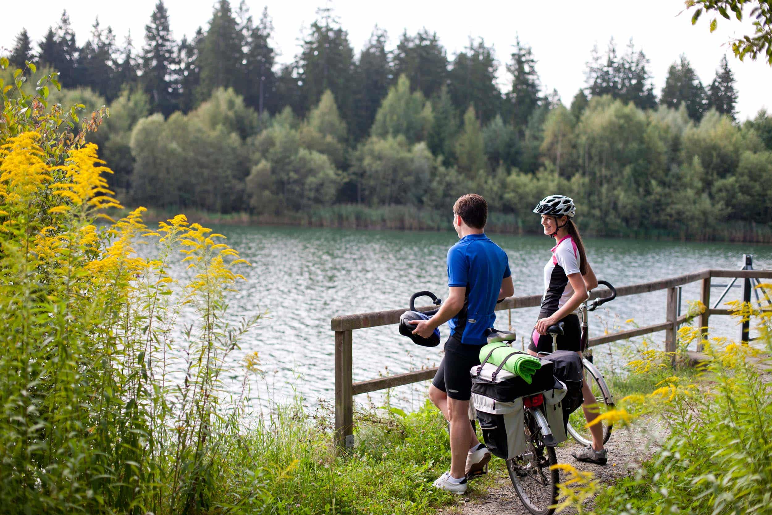 Zwei Radfahrer stehen am Seeufer und genießen die Aussicht