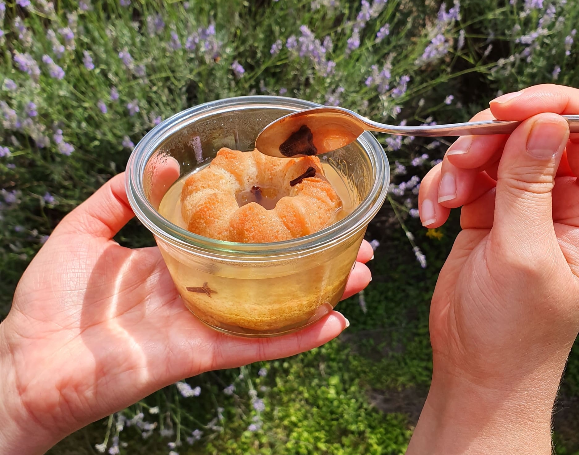 Hand holding glass with jelly and cake ring, spoon touching jelly