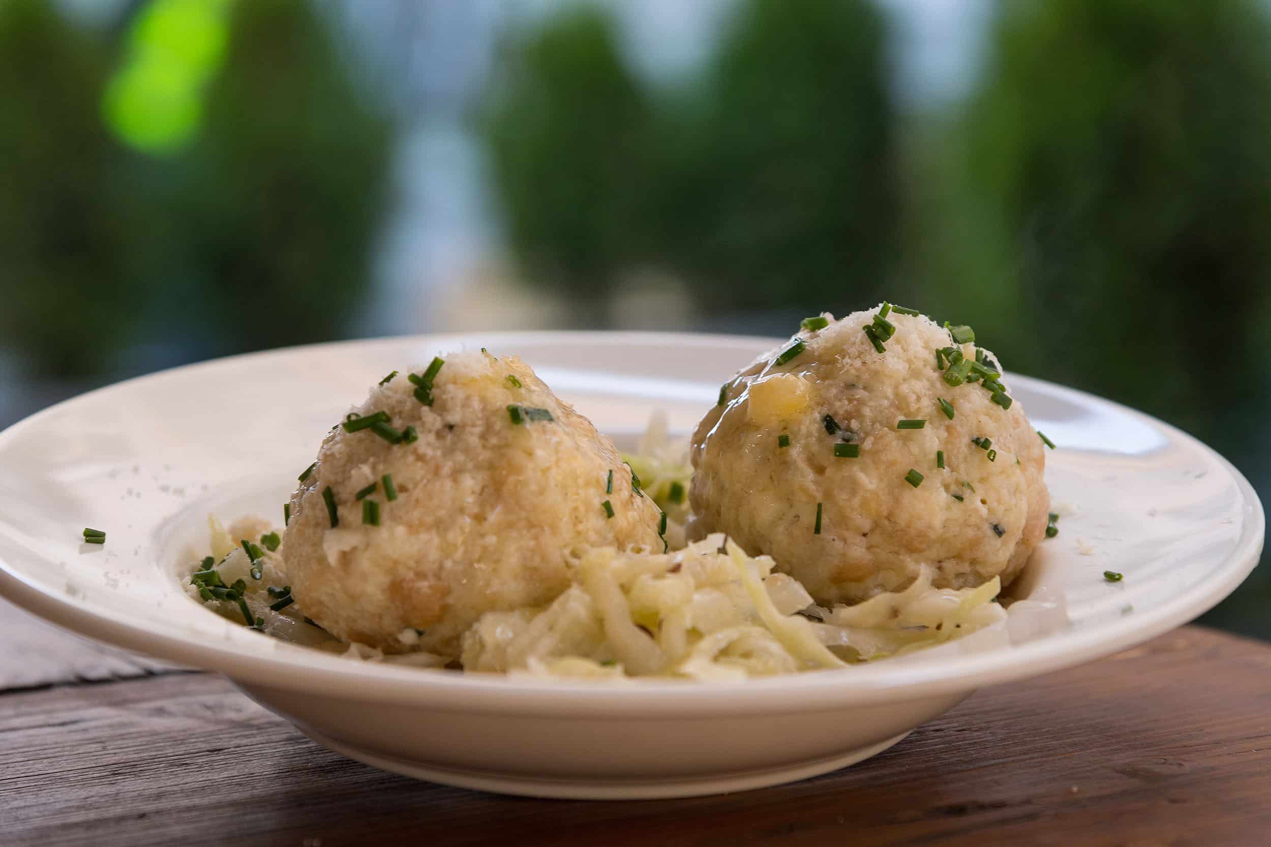 Two bread dumplings with chopped herbs on a plate