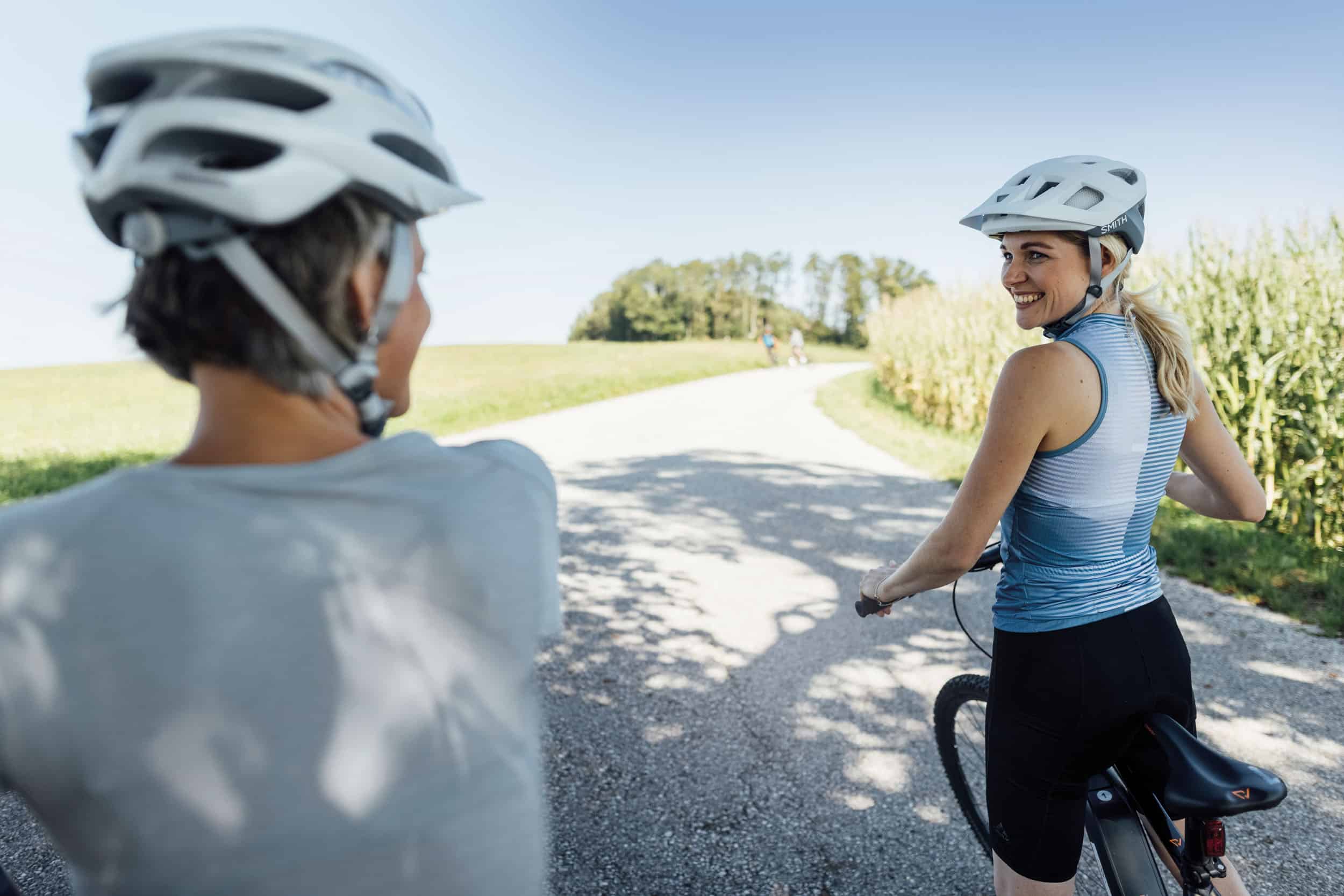 Zwei Radfahrer mit Helmen auf einem Landweg bei sonnigem Wetter