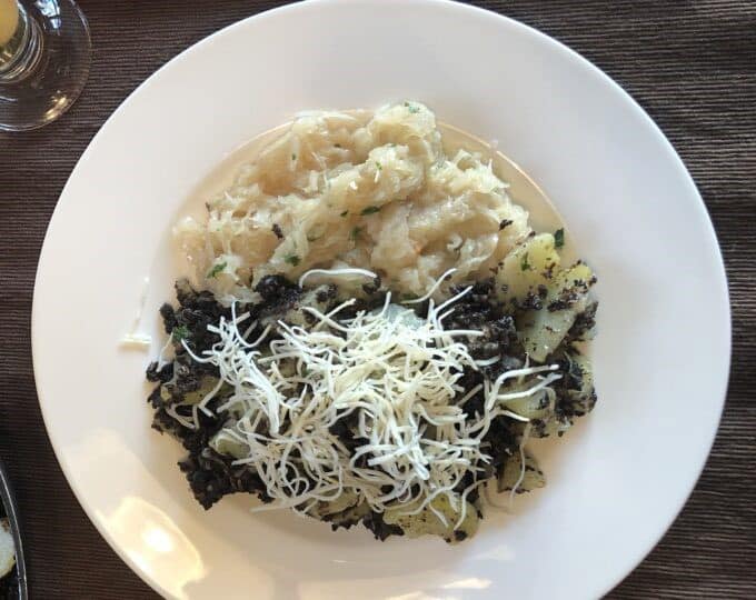 Plate with potatoes, black topping, and shredded cheese