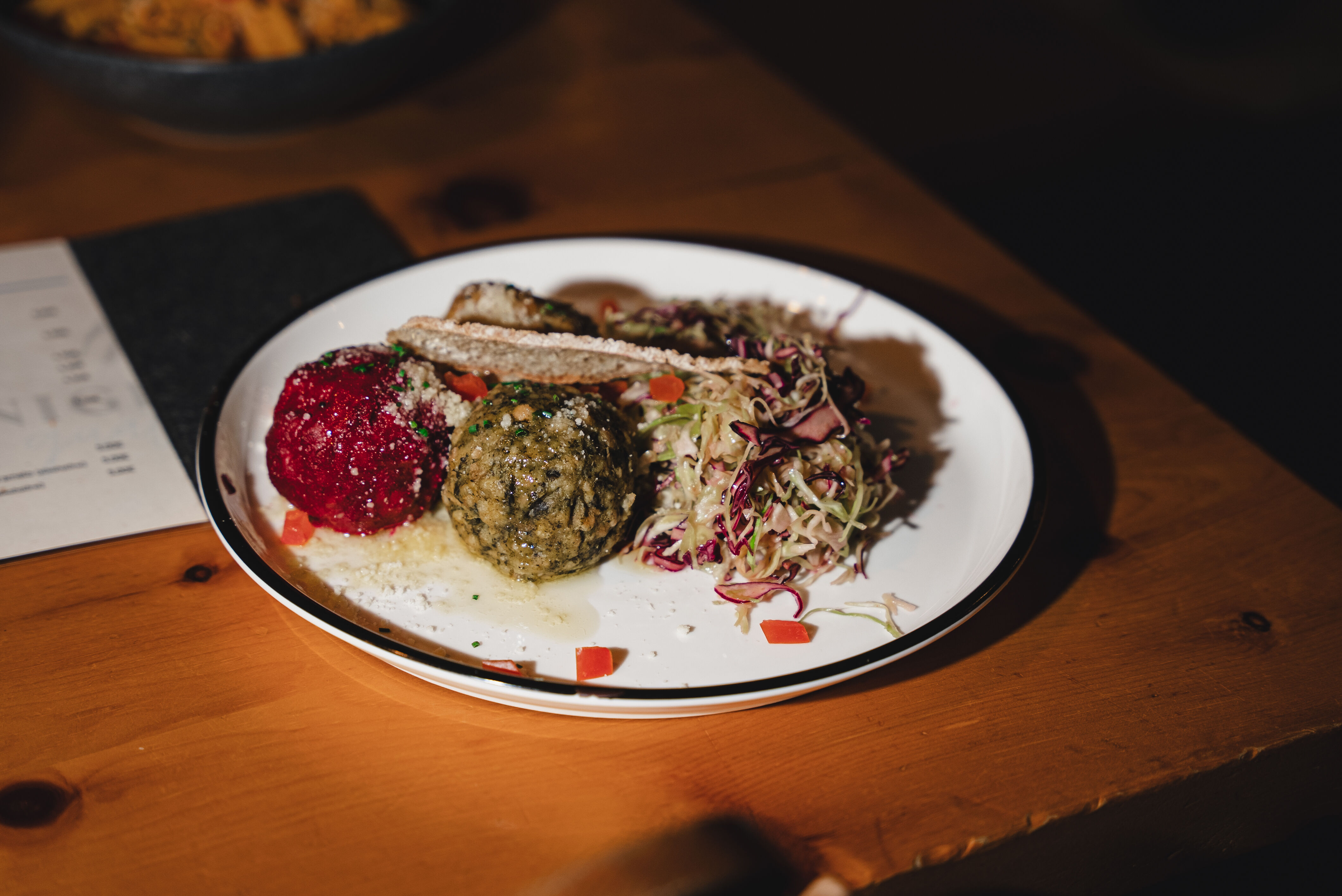 Teller mit zwei Klößen und Krautsalat auf Holztisch