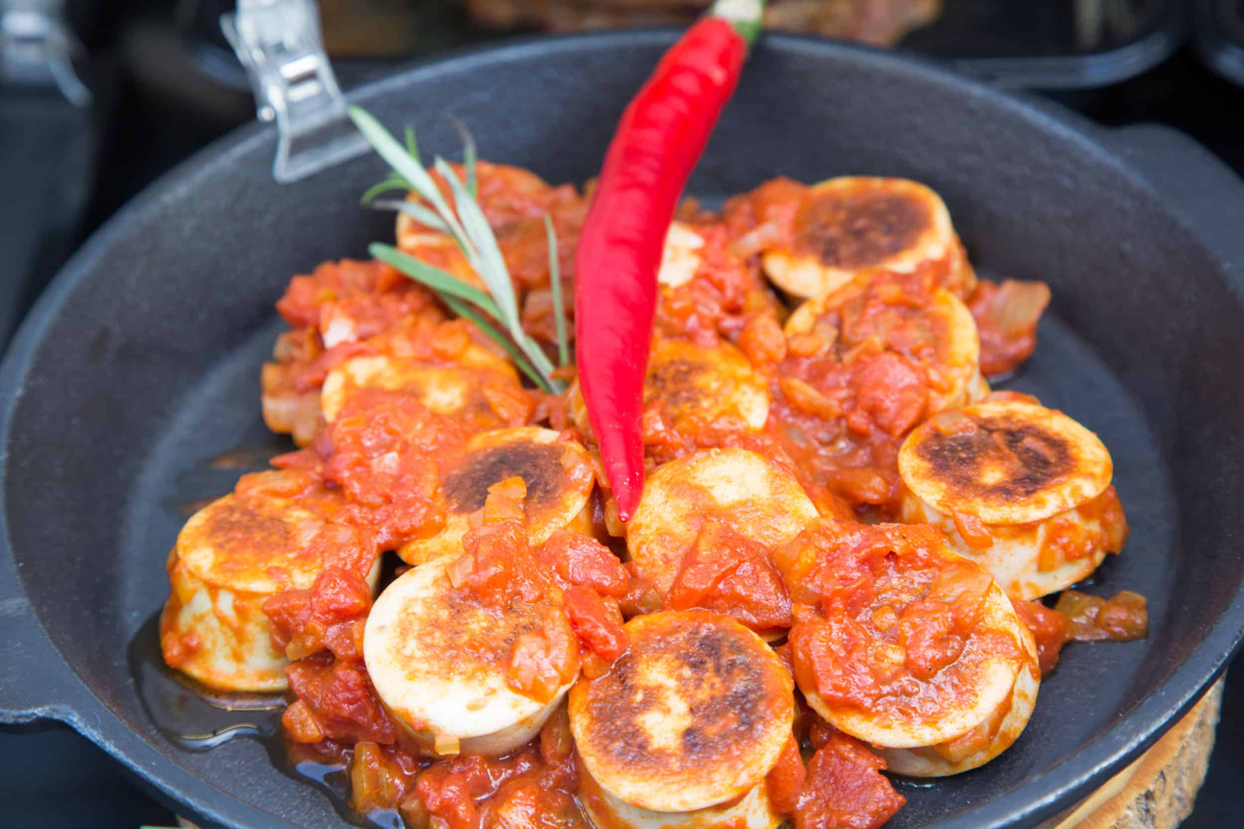Fried vegan sausages in tomato sauce with red chili in a pan