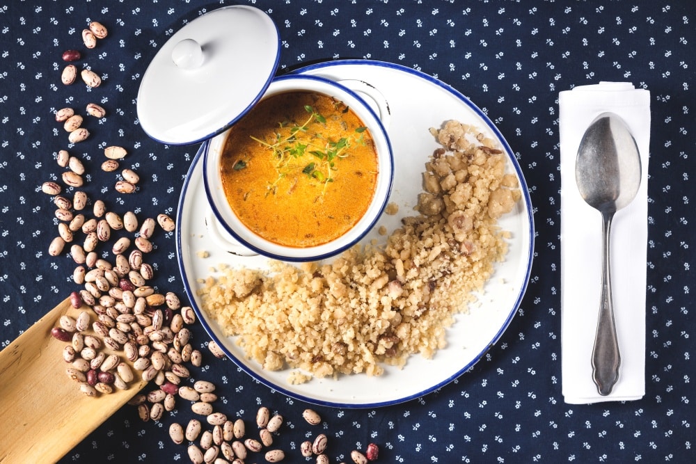 Millet with bean soup in white dish on blue cloth with spoon