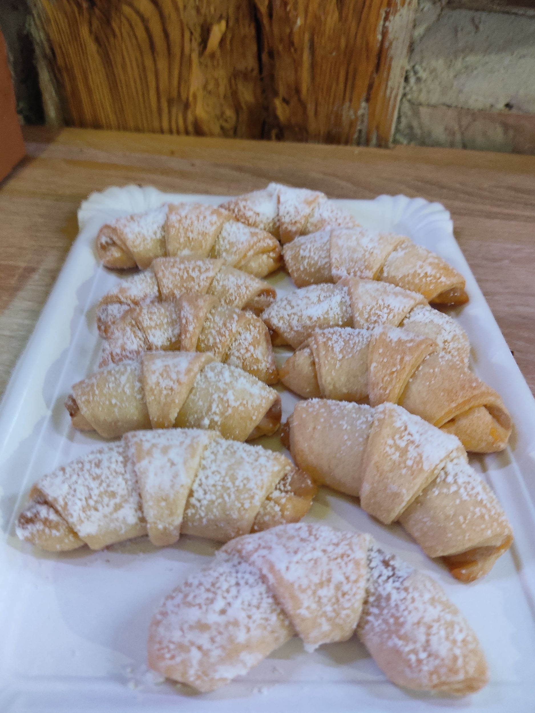 Several mini croissants dusted with powdered sugar on a white tray