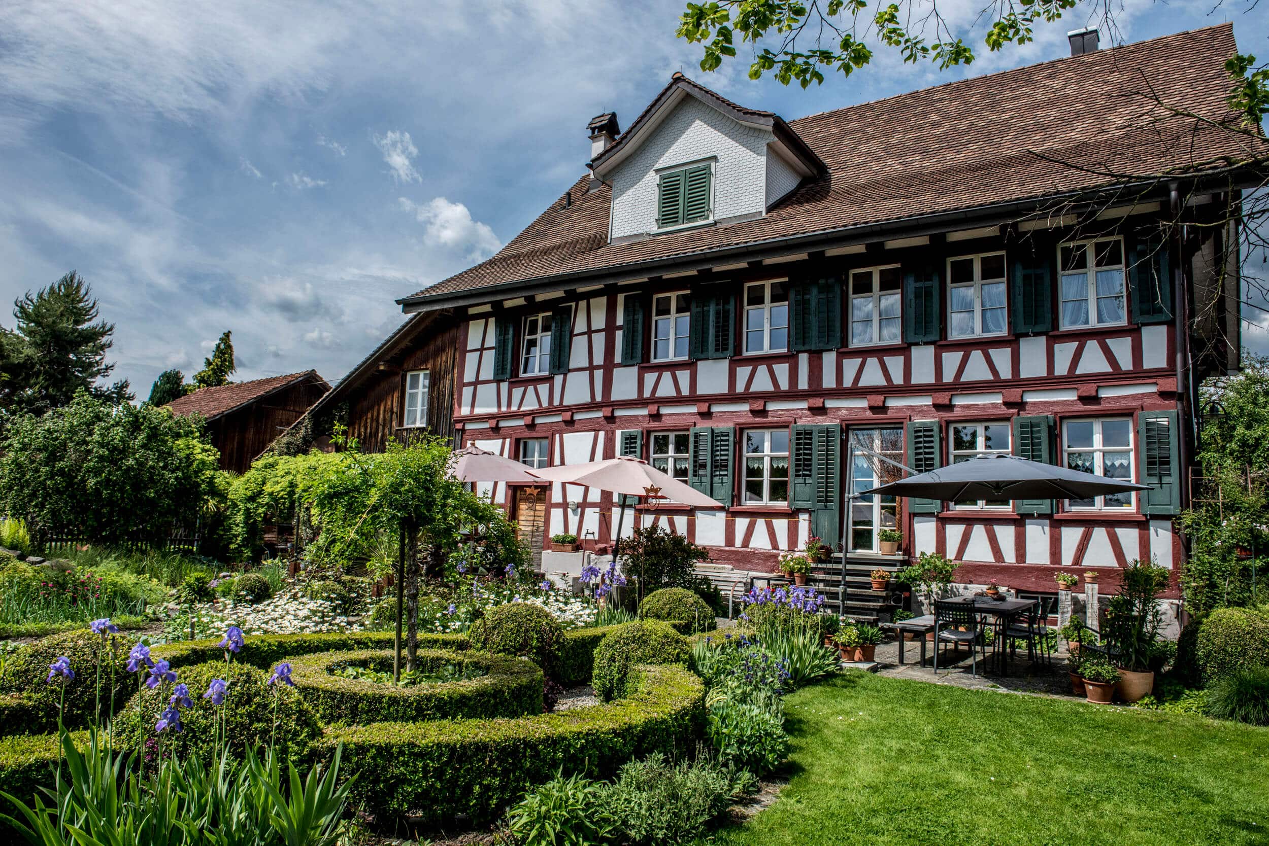 Fachwerkhaus mit gepflegtem Garten und blühenden Blumen bei sonnigem Himmel