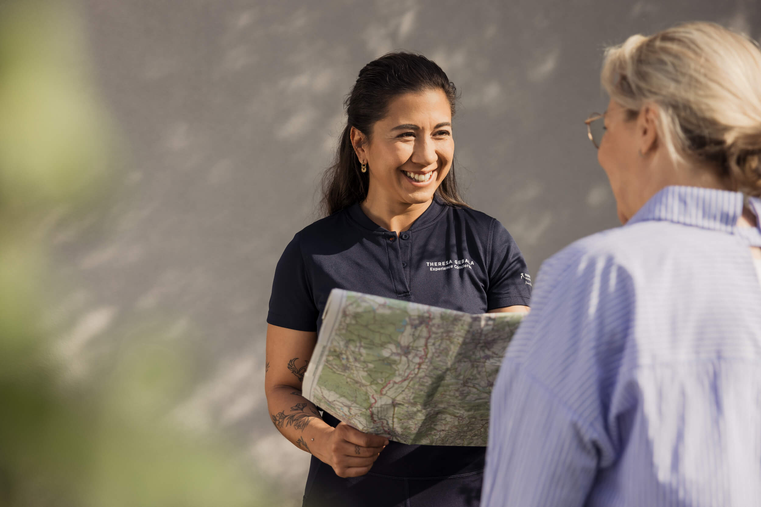 Frau zeigt einer anderen Frau eine Karte und lächelt freundlich