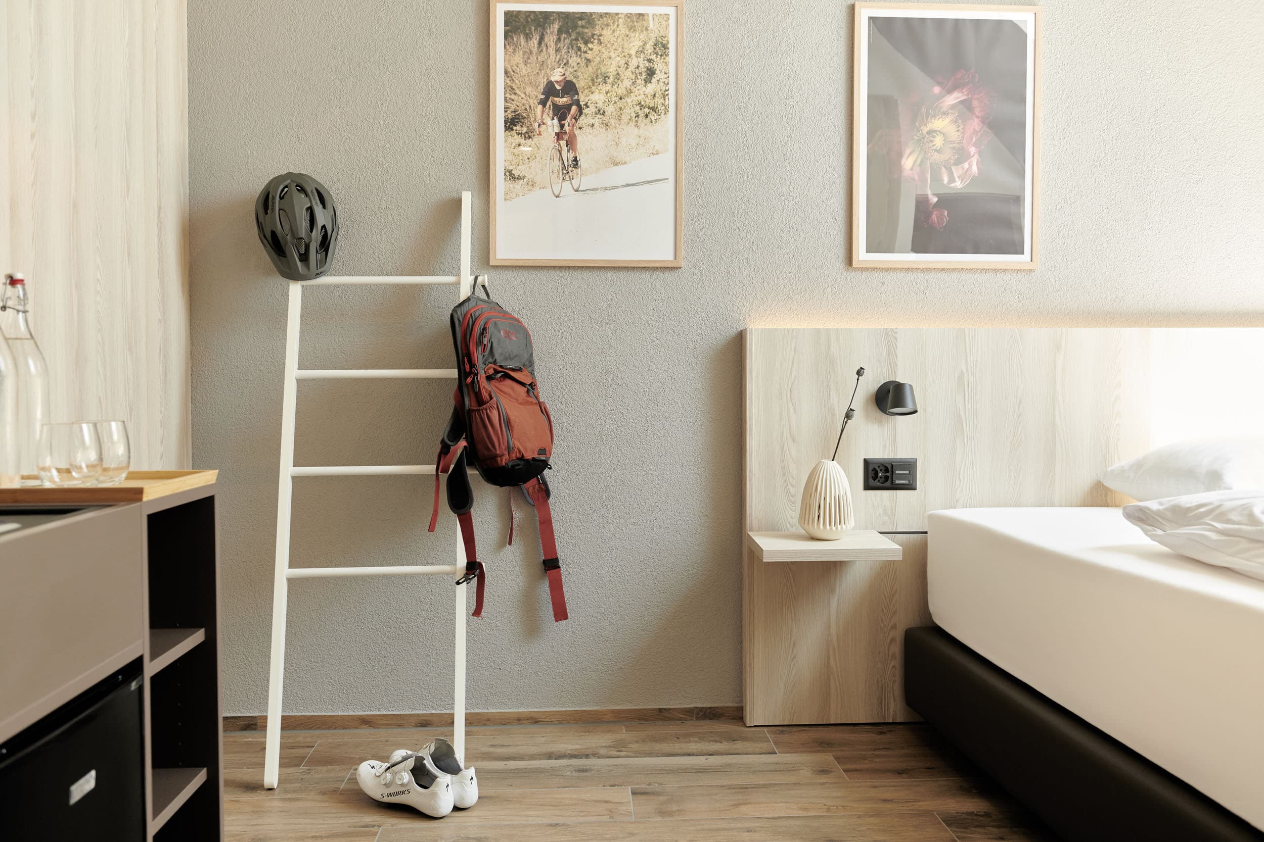 Hotelzimmer mit Fahrradzubehör neben einem Bett und dekorativen Bildern