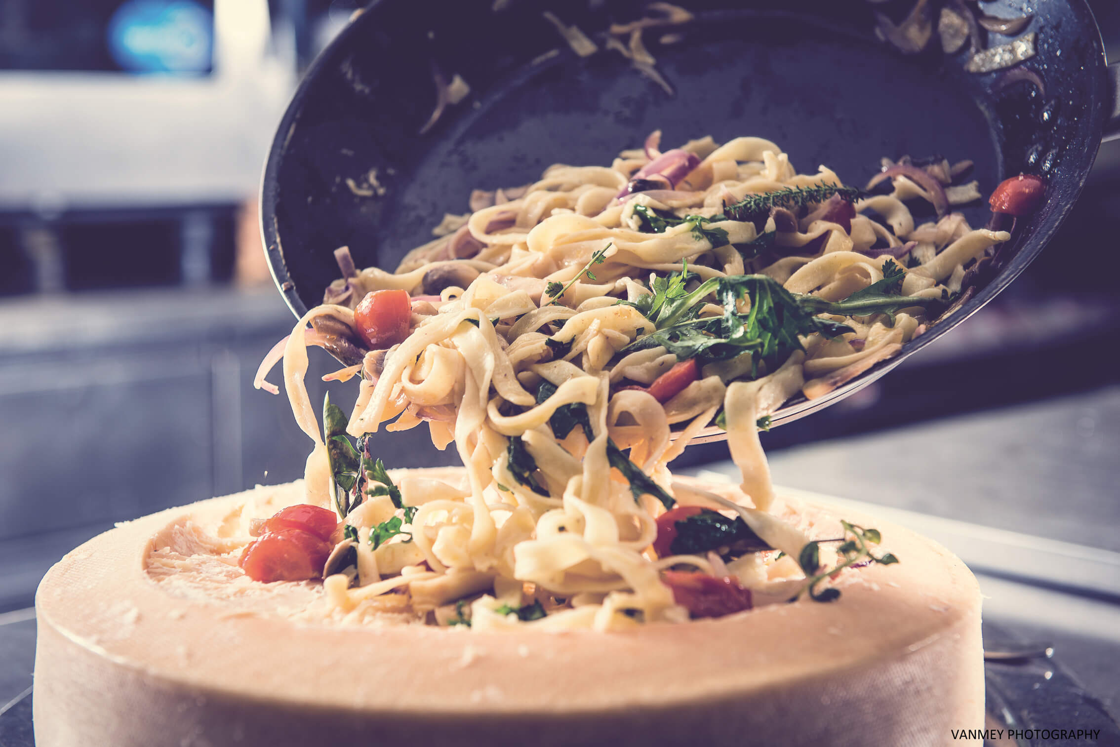 Pasta with vegetables being served inside a large cheese wheel