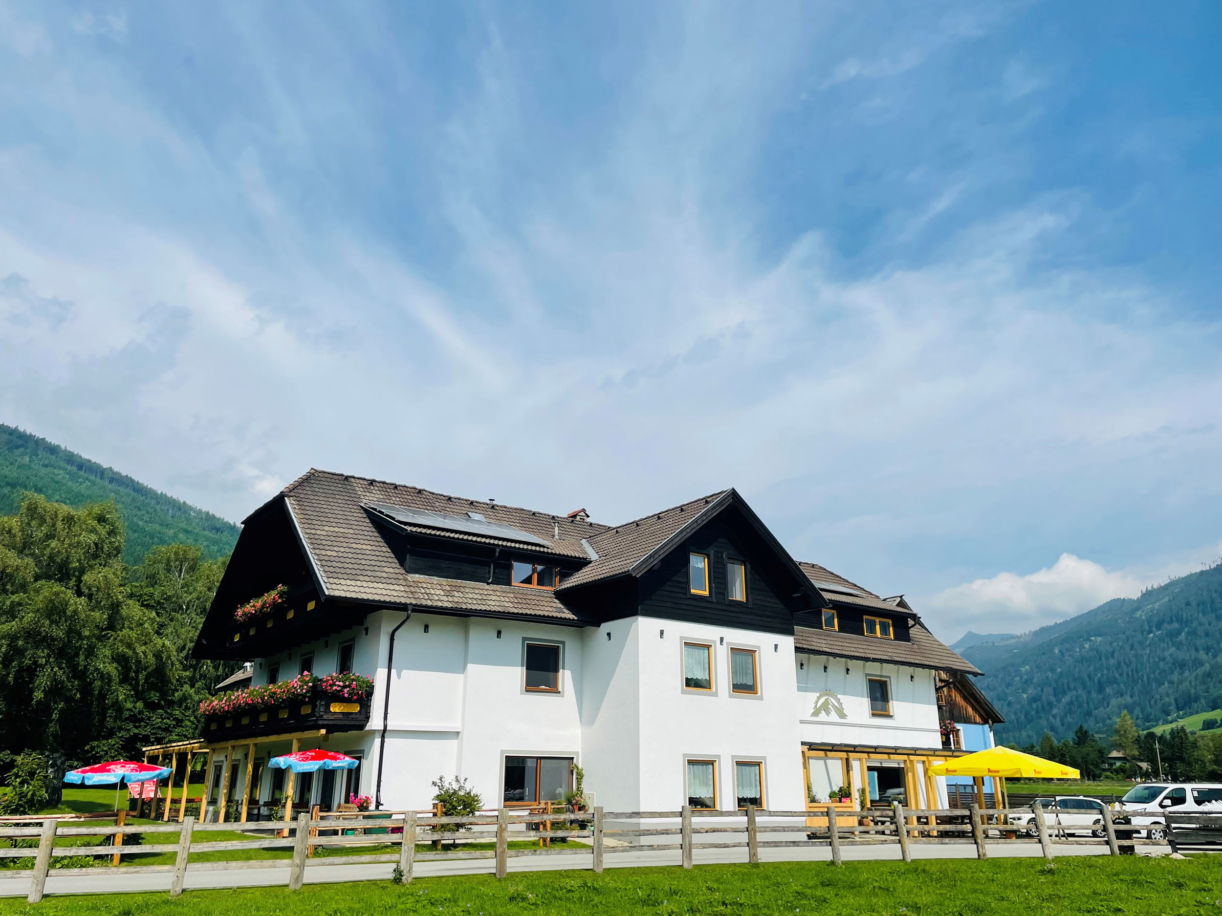 Large white house with brown roof and mountains in the background