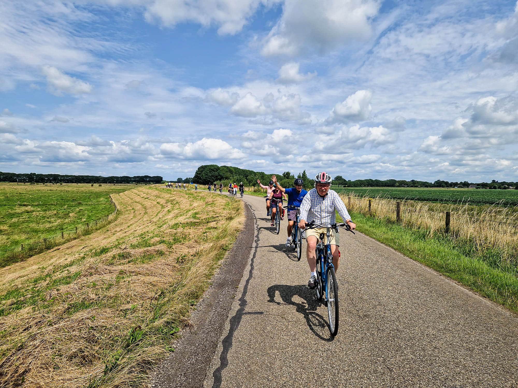 Gruppe von Radfahrern fährt auf Landstraße bei bewölktem Himmel