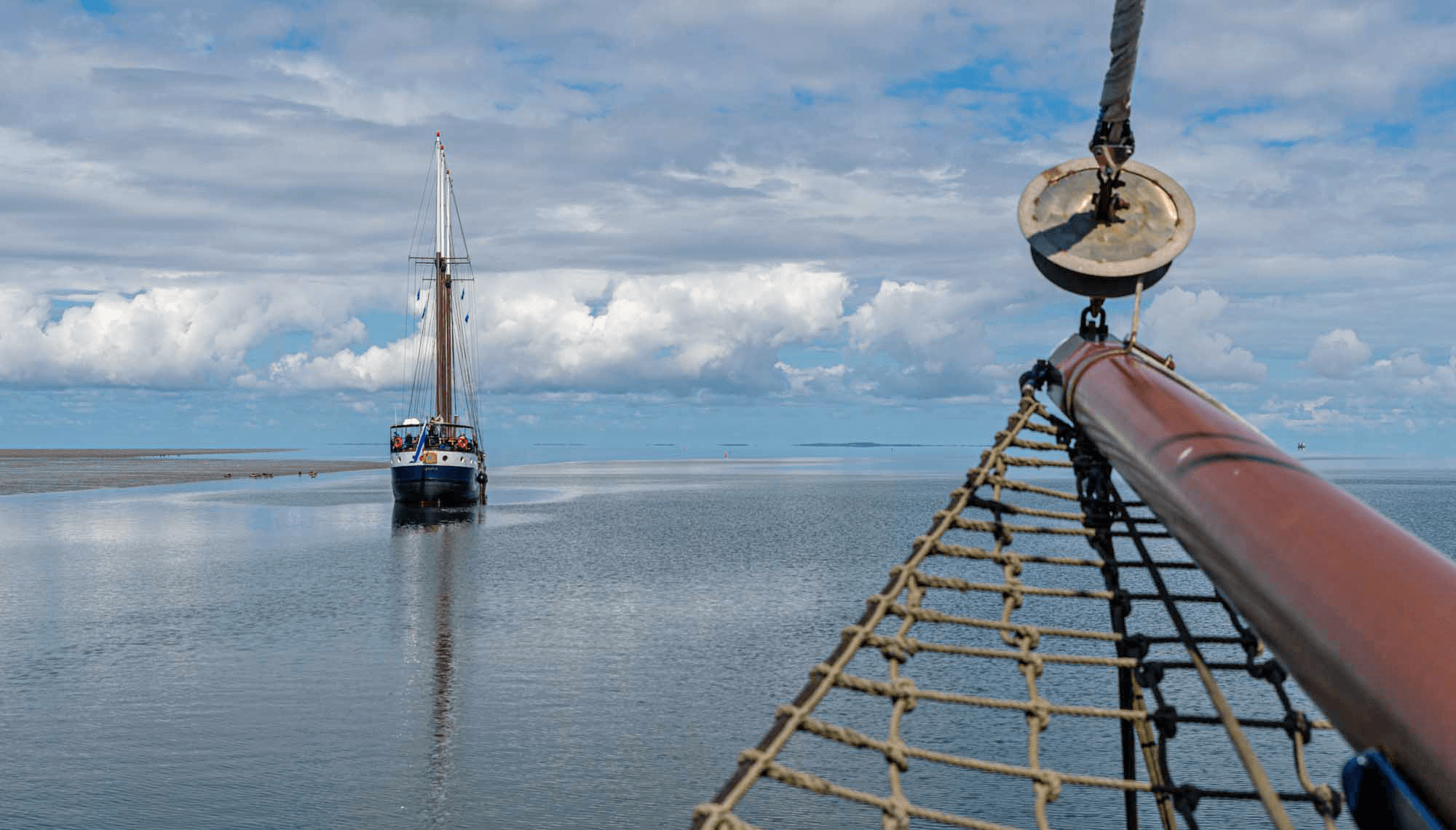 Segelboot auf ruhigem Wasser unter bewölktem Himmel
