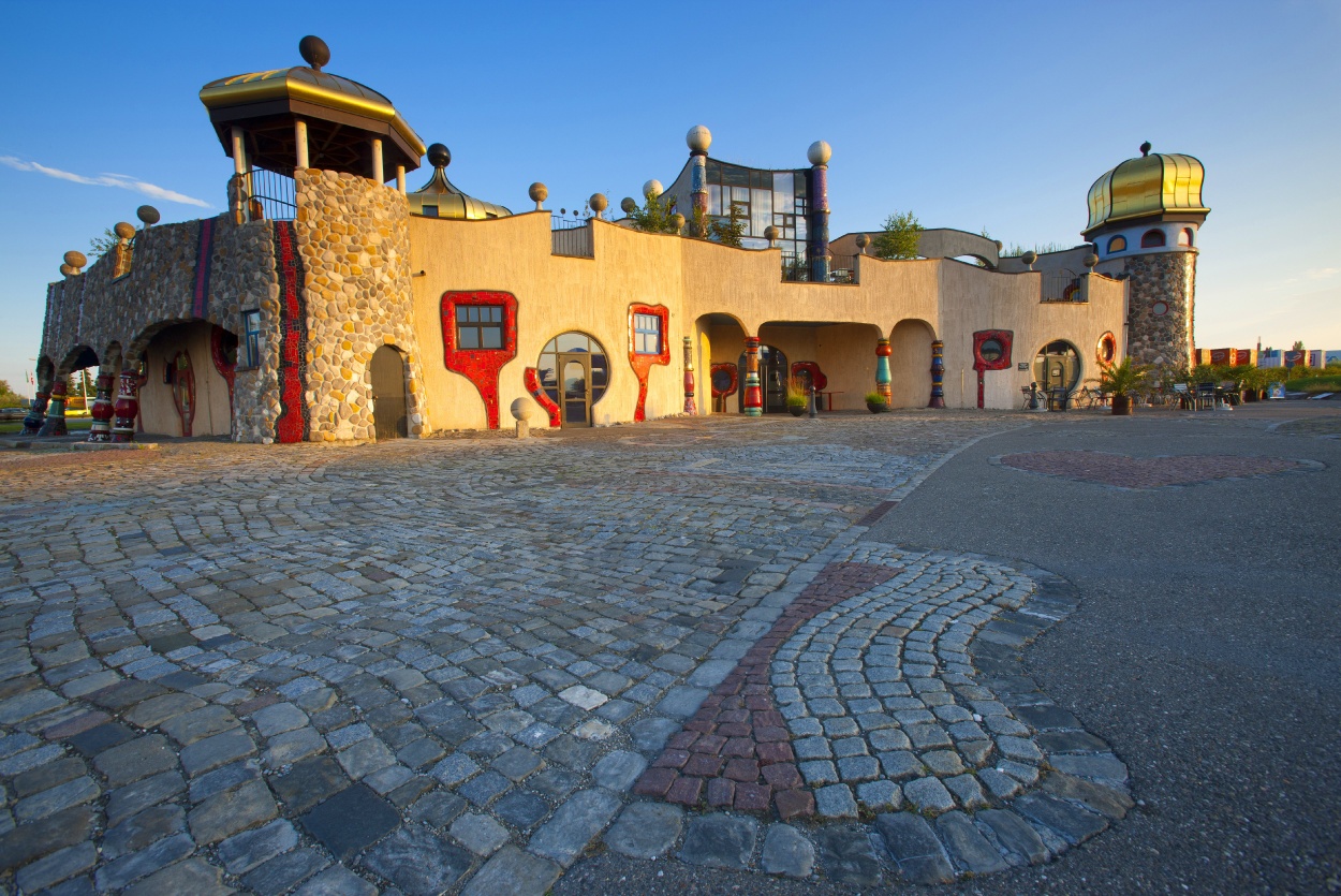 Artistic building with golden domes and cobblestone courtyard at sunset